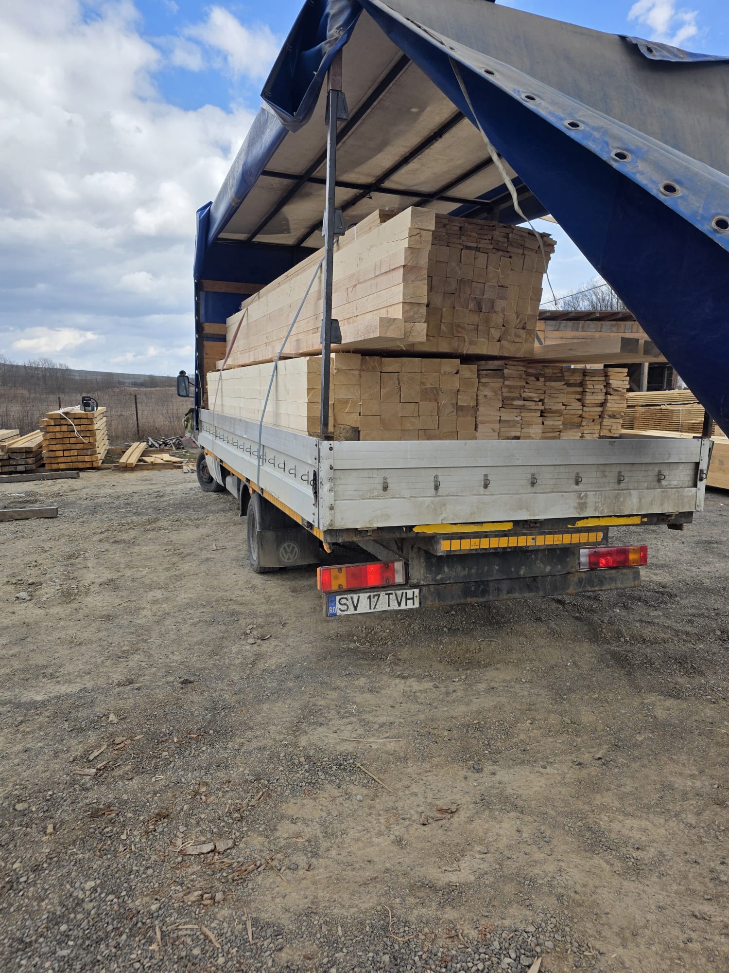 Camion cu prelată încărcat cu grinzi de lemn pentru livrare în județul Suceava